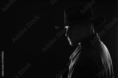 Old fashioned detective in hat on dark background  black and white effect. Space for text