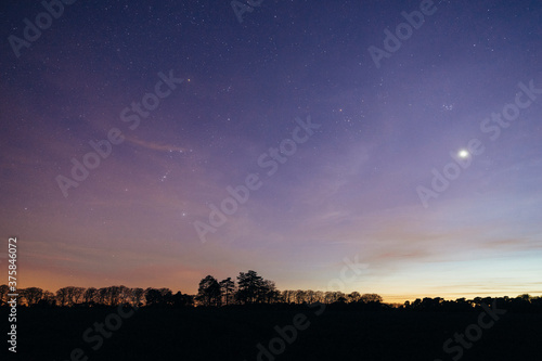 Venus, The Pleiades and Orion over rural landscape at night. photo