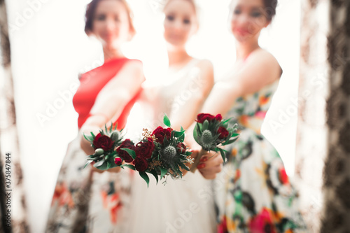 Bride with bridesmaids holding wonderful luxury wedding bouquet of different flowers on the wedding day