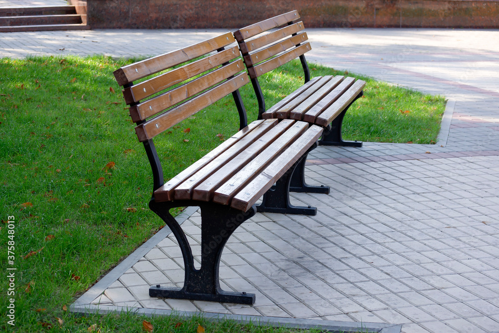 Two wooden benches on cement floor at park Two wooden benches on cement floor at park