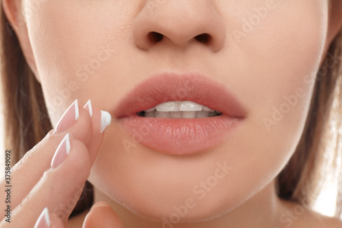 Young woman with cold sore applying cream on lips  closeup