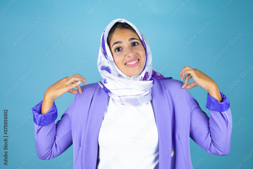 Young beautiful arab woman wearing islamic hijab over isolated blue background with a successful expression