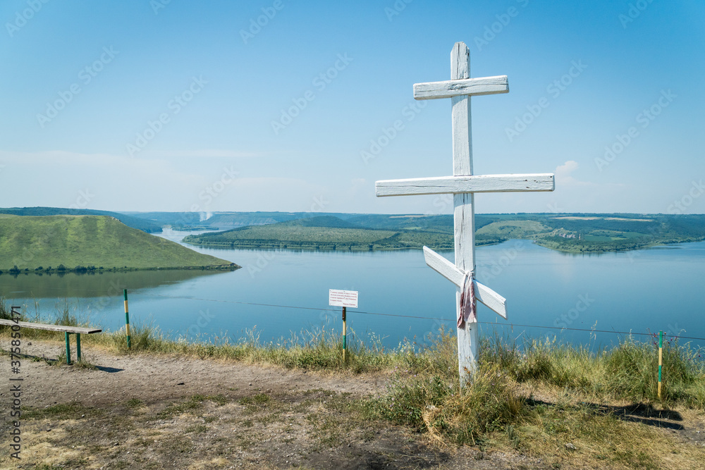 View point on hill marked with a white wooden christian cross with a view on Bakota Bay, located over flooded Bakota village in Khmelnytskyi region, Ukraine. View point on hill marked with a white wooden christian cross with a view on Bakota Bay, located over flooded Bakota village in Khmelnytskyi region, Ukraine.