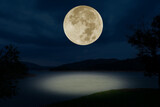 full moon over the lake at night.