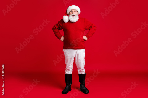 Full length photo of old man in santa claus headwear put hands waist enjoy dream advent newyear event holiday wear sweater pants isolated over bright shine color background