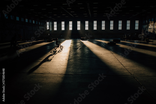 Young child rides a bike through a beam of light, silhouette and shadow photo