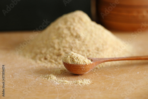 Crushed flax seeds (ground linseed) on wooden spoon and table - healthy organic vegan vegetarian food ingredient