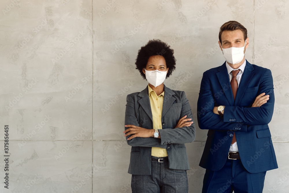 Two happy business colleagues with face masks standing with arms crossed and looking at camera. Two happy business colleagues with face masks standing with arms crossed and looking at camera.