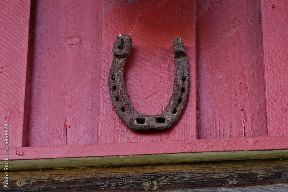 Old rusted horse shoe on a red barn wall for good luck.