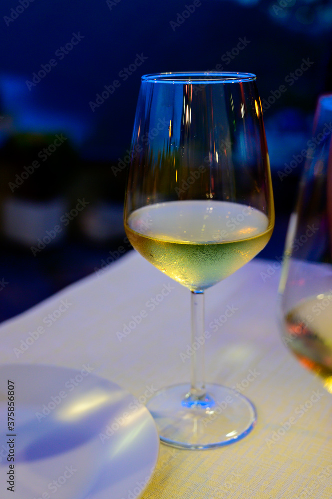Obraz premium Glass of cold dry white wine served outdoor in cafe at night in Italy