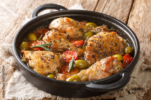 French food chicken baked with olives, tomatoes and onions, herbs close-up in a frying pan on the table. horizontal