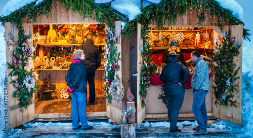 Romantic Christmas market with illuminated shops in wooden huts with gifts and handmade decoration. © Wolfilser