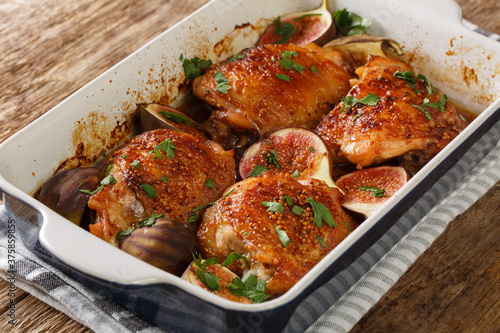 baked chicken thighs with figs and herbs close-up in a baking dish on the table. horizontal