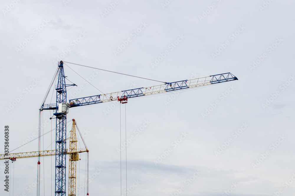 Construction site with high cranes against the blue sky