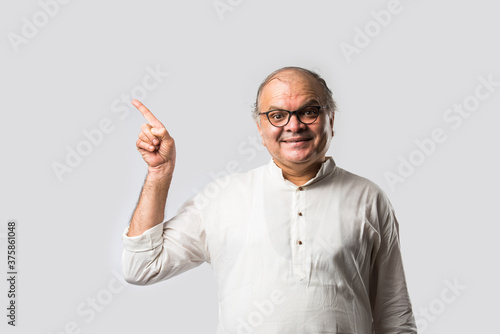 Фотография Portrait of cheerful Indian senior old man pointing or presenting or in hands fo