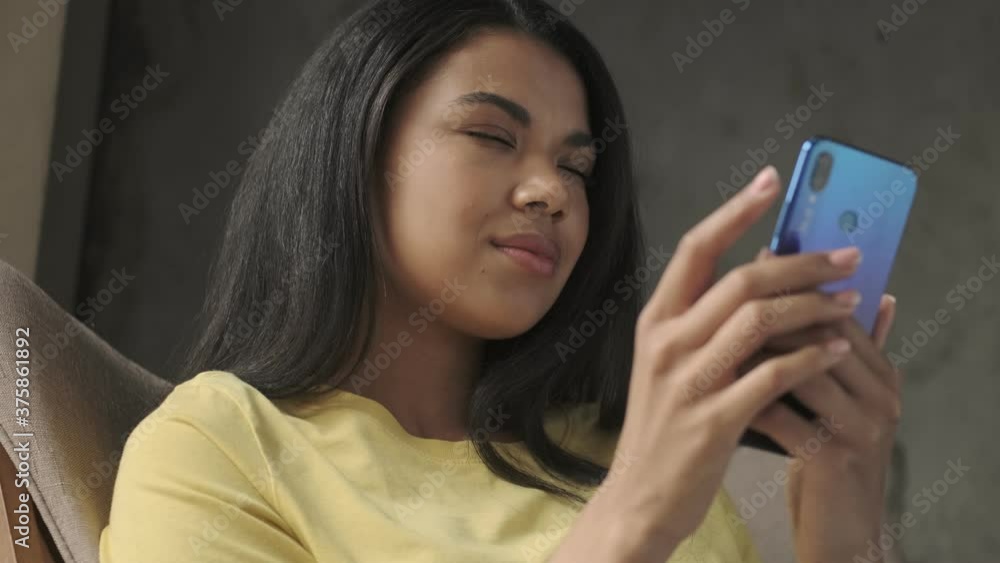 Young thinking positive woman using mobile phone indoors at home Young thinking positive woman using mobile phone indoors at home