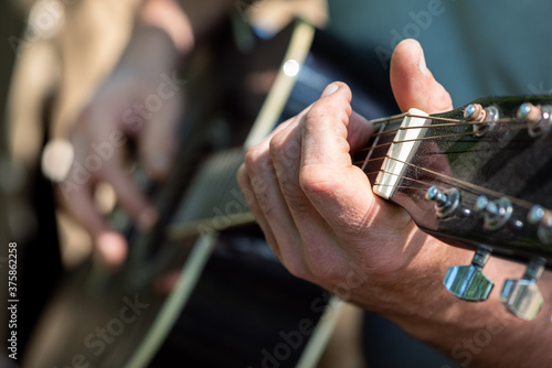 Man playing classical guitar sitting near tent outdoors. Closeup of hands. Selective focus. Summer vacation and traveling concept.
