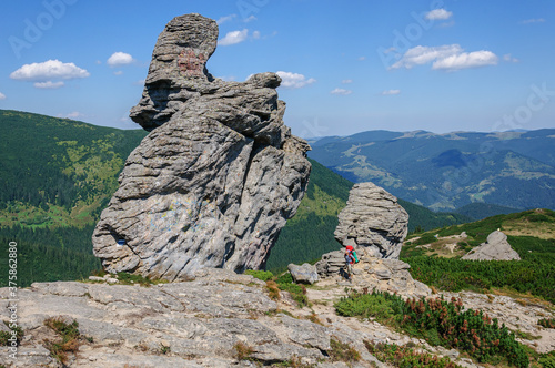 A man with a large backpack looks at the Vysokaya rock in the carpathian mountains Ukraine photo