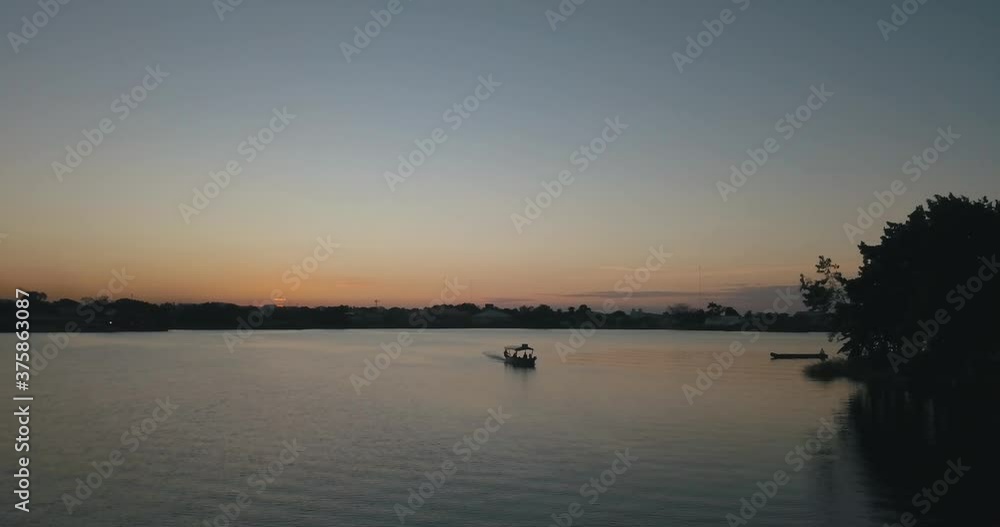 Sunset drone aerial of a boat driving through the lake of Flores Peten, Guatemala Sunset drone aerial of a boat driving through the lake of Flores Peten, Guatemala