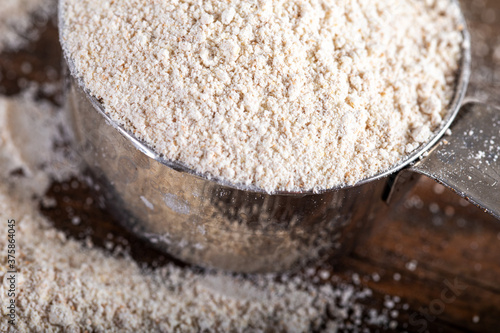 Einkorn siyez whole wheat flour in metal measuring cup on natural background. photo