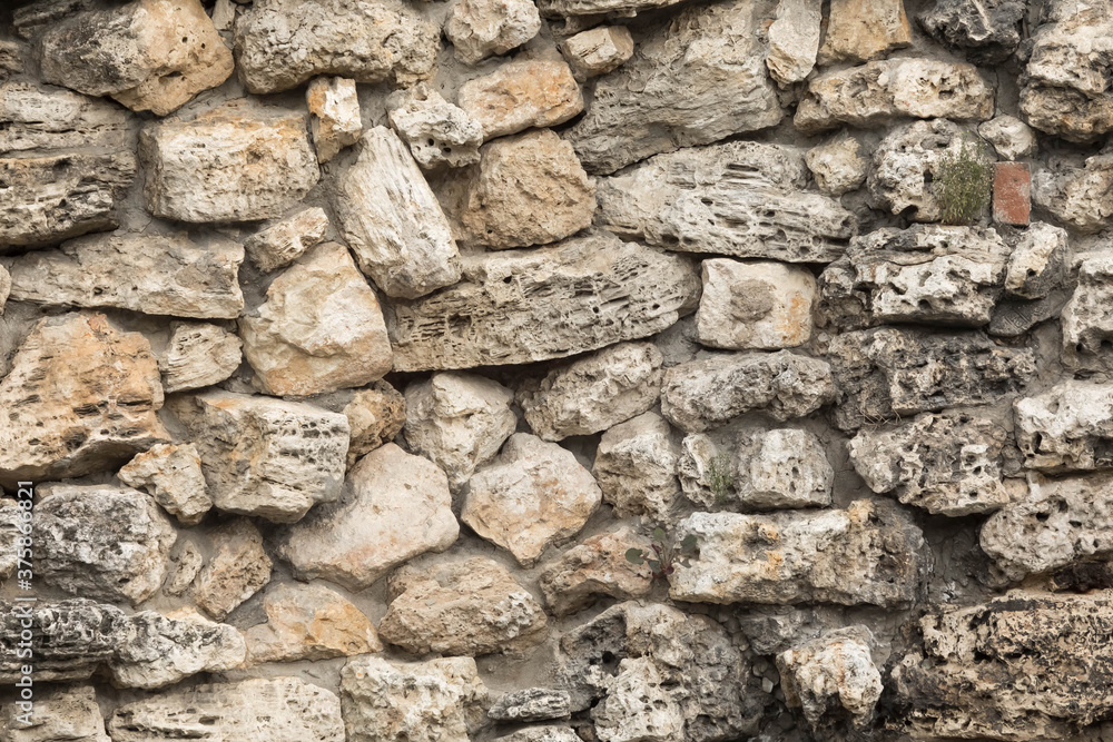 background of the antique wall of the old stone. Weathered surface. Stones of different sizes and shapes background of the antique wall of the old stone. Weathered surface. Stones of different sizes and shapes