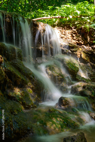 Fototapeta Naklejka Na Ścianę i Meble -  Small forest waterfall on a Sunny summer day