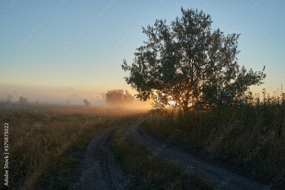 Autumn time. Dawn over the river in a misty, brooding haze. Beautiful view of the forest and river, covered with fog in the early morning. The sun's rays of light. September. Autumn time. Dawn over the river in a misty, brooding haze. Beautiful view of the forest and river, covered with fog in the early morning. The sun's rays of light. September.