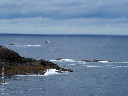 Pescador lanzando las redes de pesca al agua desde el barco, costa atlàntica gallega, la coruña, españa, europa,