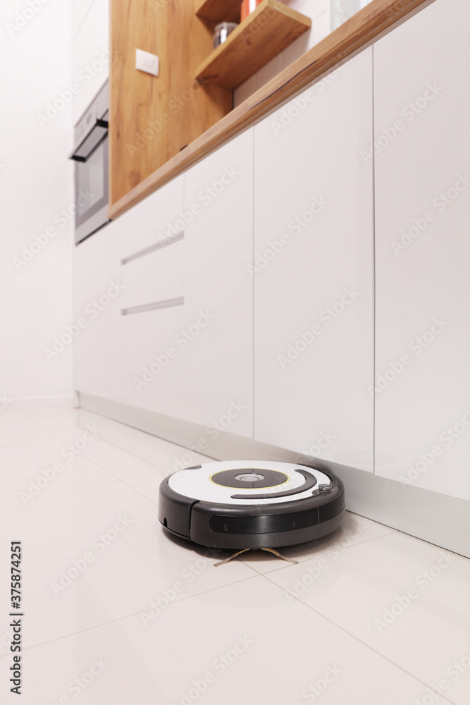 Robotic vacuum cleaner working on a kitchen floor Robotic vacuum cleaner working on a kitchen floor