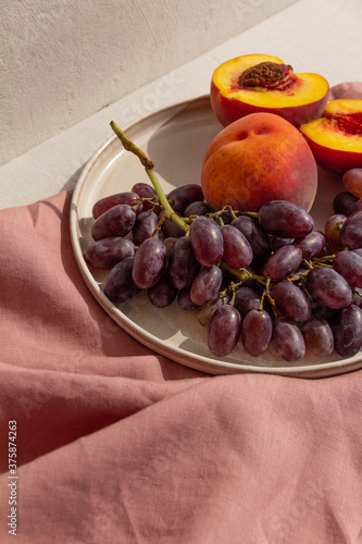 juicy fresh peaches and grapes on a plate on a light background
