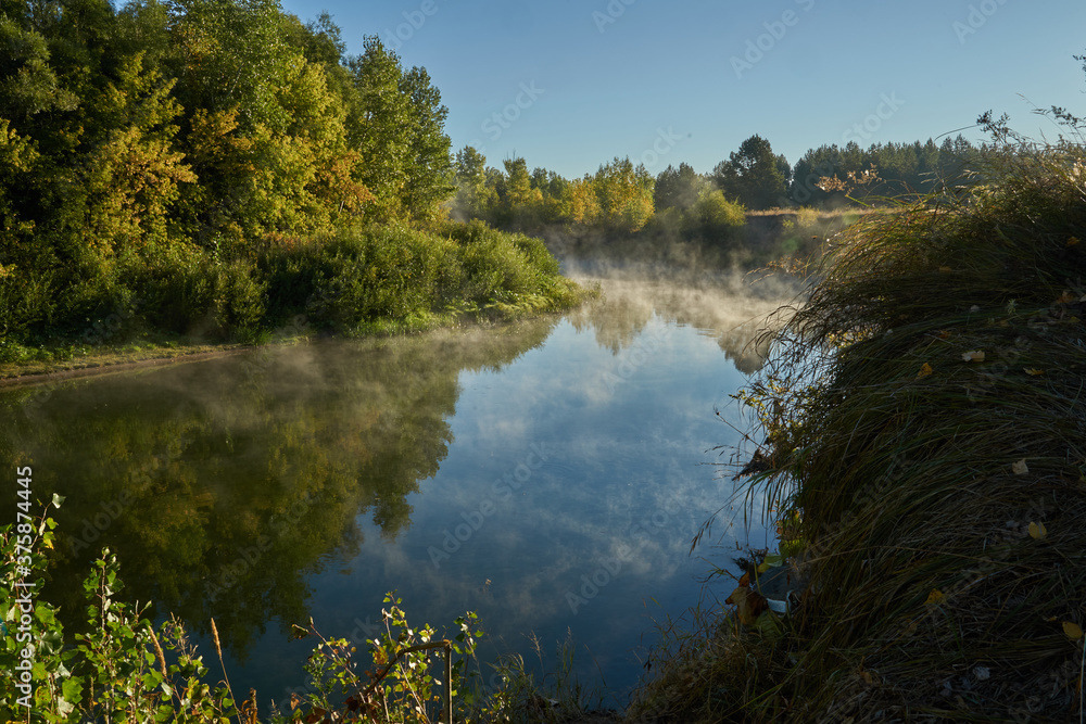 Autumn time. Dawn over the river in a misty, brooding haze. Beautiful view of the forest and river, covered with fog in the early morning. The sun's rays of light. September. Autumn time. Dawn over the river in a misty, brooding haze. Beautiful view of the forest and river, covered with fog in the early morning. The sun's rays of light. September.