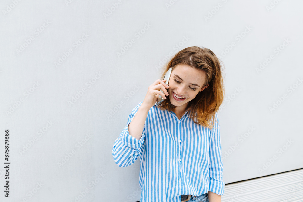 Young woman smiling as she chats on her mobile Young woman smiling as she chats on her mobile