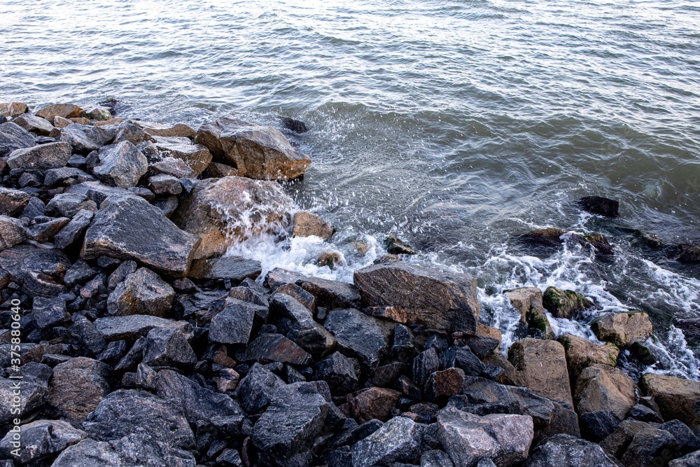 stone and sand seashore with waves in the sunset light stone and sand seashore with waves in the sunset light