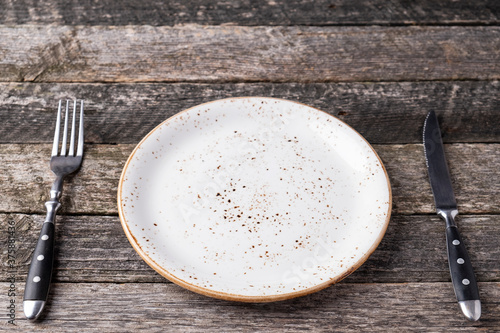 Empty plate with fork and knife over wooden background