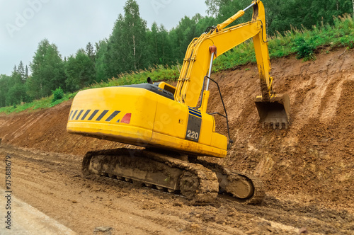 Road widening works (highway construction). Crawler excavator digs the ground with a bucket.