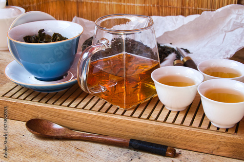 Chinesisches Teeset mit Gaiwan, Gong Dao Bei und weißen Porzellanbechern auf Holztablett für Gongfu Teezubereitung photo