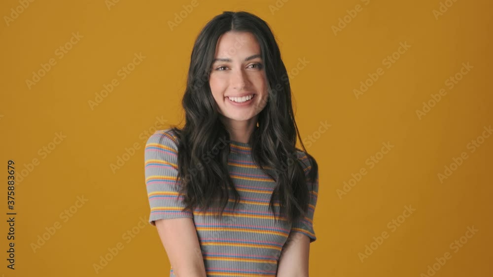 A positive young woman is posing standing isolated over yellow background A positive young woman is posing standing isolated over yellow background