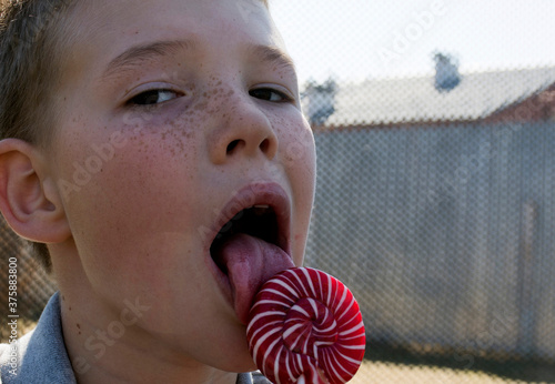 The boy is eating a delicious lollipop. The boy is eating a delicious lollipop. The boy licks the lollipop. Lollipop. photo