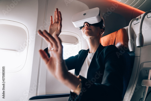Curious formal woman using VR glasses in airplane