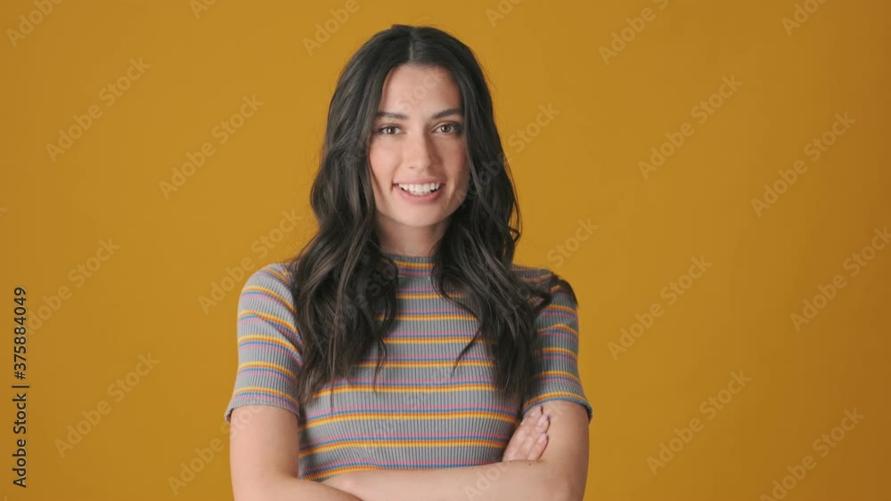A beautiful happy young woman is gesturing and showing different emotions standing isolated over yellow background A beautiful happy young woman is gesturing and showing different emotions standing isolated over yellow background