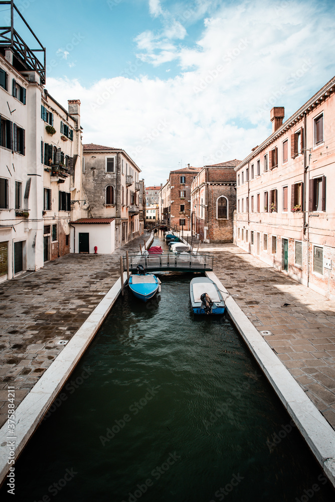Narrow canal with boats in Venice Italy
