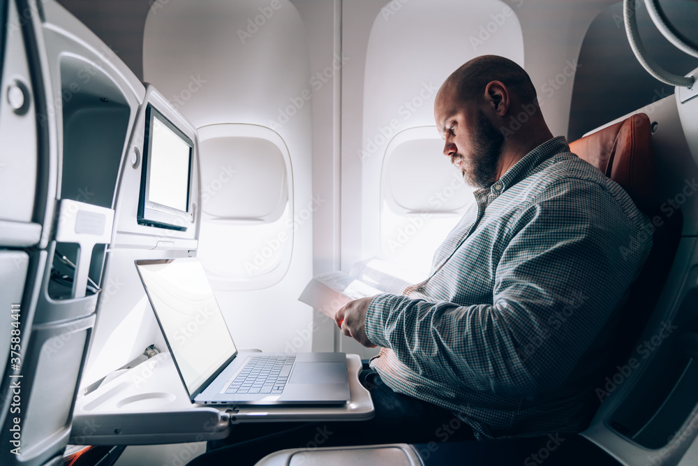 Focused man reading book in airplane Focused man reading book in airplane