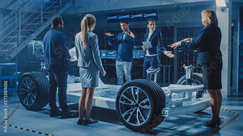 Shot of International Team of Automobile Design Engineers Introducing Futuristic Autonomous Electric Car Platform Chassis to a Group of Investors and Businesspeople. © Gorodenkoff