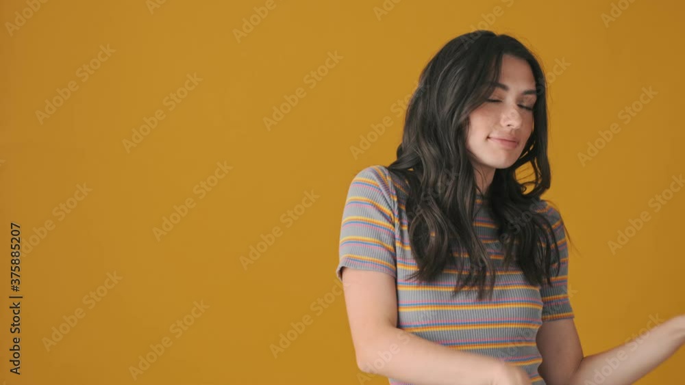 A positive young woman is dancing isolated over yellow background A positive young woman is dancing isolated over yellow background