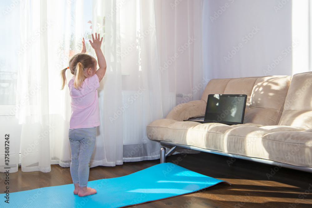 Little girl watching onlinfitness exercises. Kids sports healthy lifestyle, stay at home, online learning, online training. Little girl watching onlinfitness exercises. Kids sports healthy lifestyle, stay at home, online learning, online training.