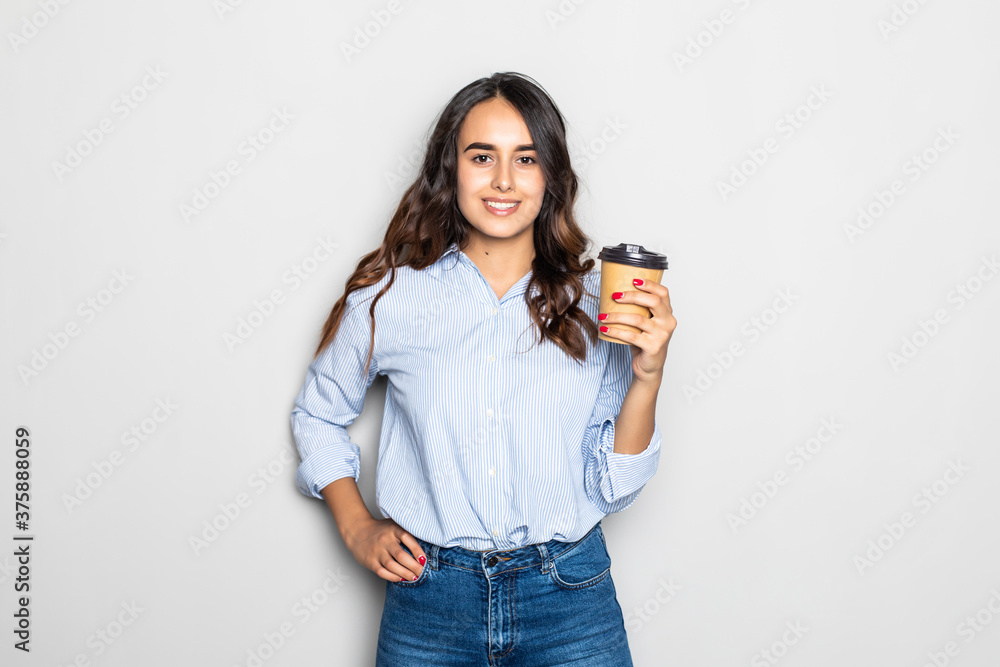 Beautiful young woman drinking hot drink from disposable paper cup, isolated over gray background Beautiful young woman drinking hot drink from disposable paper cup, isolated over gray background