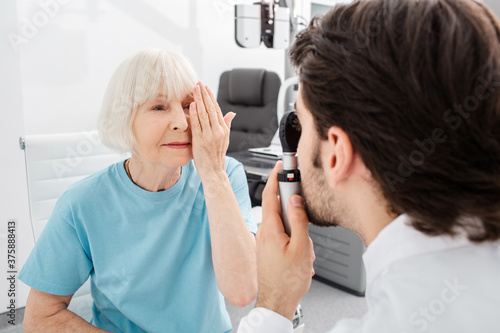 Foto Senior woman patient checking vision in optician's office