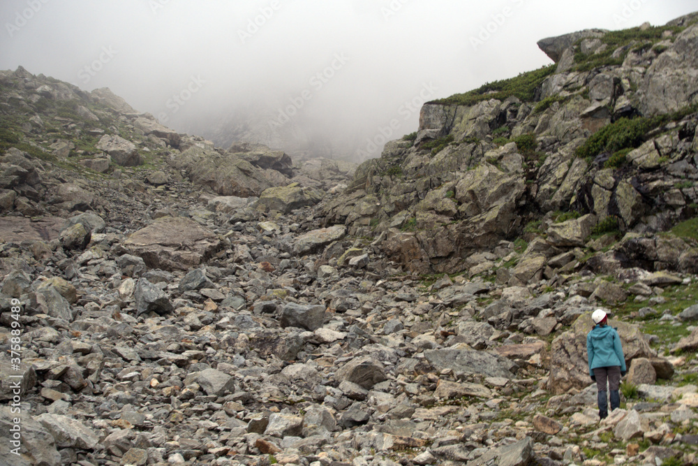 Mountain tourism. A tourist on a mountain pass in foggy weather.
