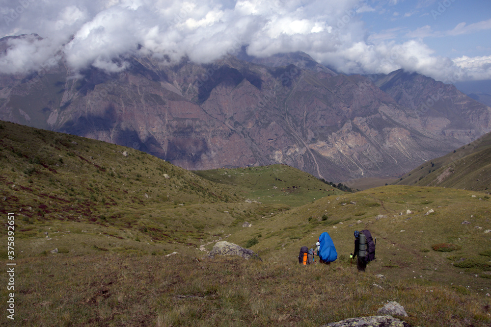 Backpackers trekking in mountains. Tourists hike through the valley. Valley near Bulungu village.