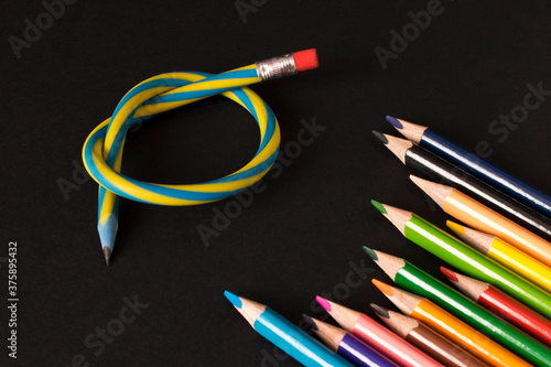Flexible pencil and a set of colored pencils on a dark background. Selective focus.